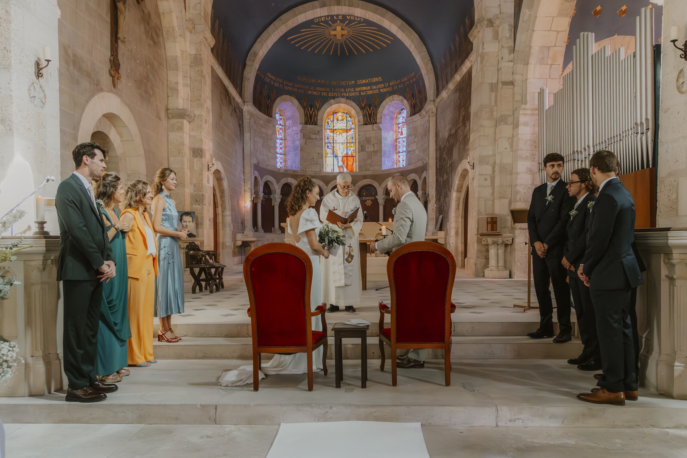 Mathilde et Henri devant l’autel pendant leur cérémonie religieuse, entourés de leurs témoins, sous les vitraux de l’église