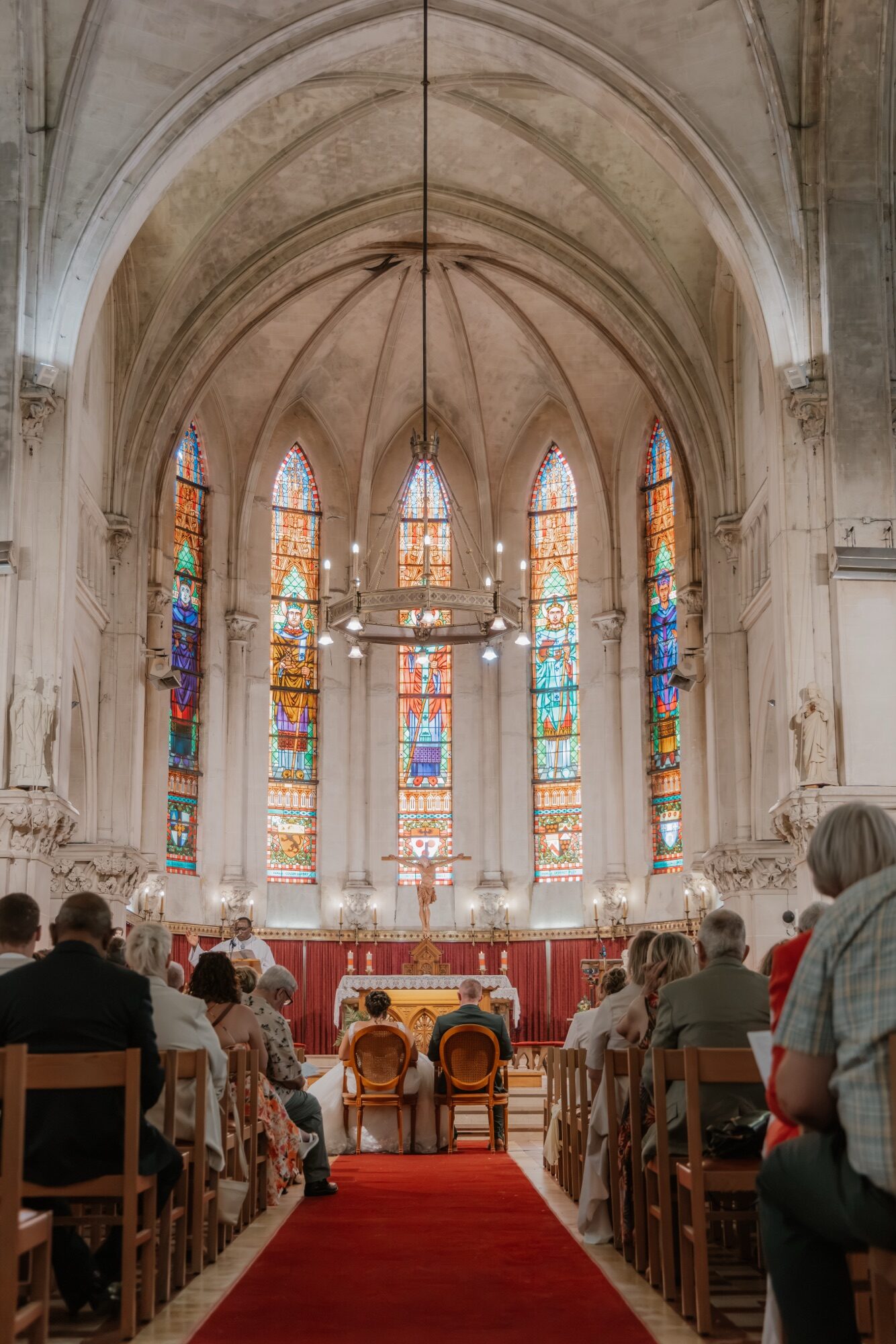 La cérémonie de Leena et Jonah dans une église aux grands vitraux, sous de hautes voûtes