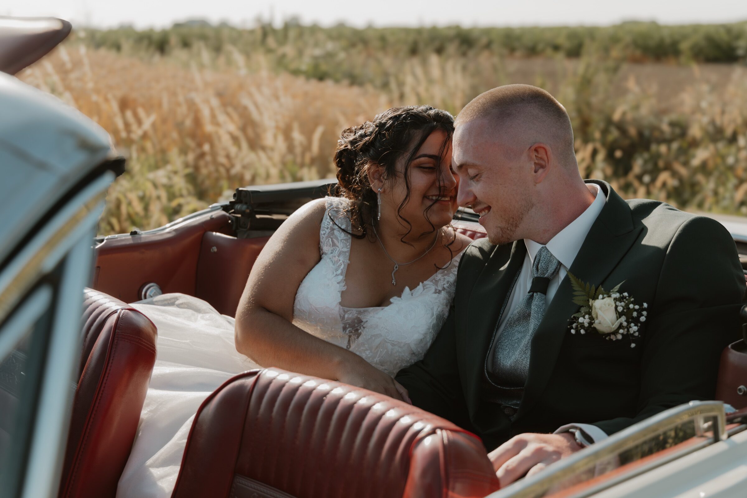 Leena et Jonah, front contre front dans une décapotable de collection au milieu des champs dorés — photo de mariage près de Lille