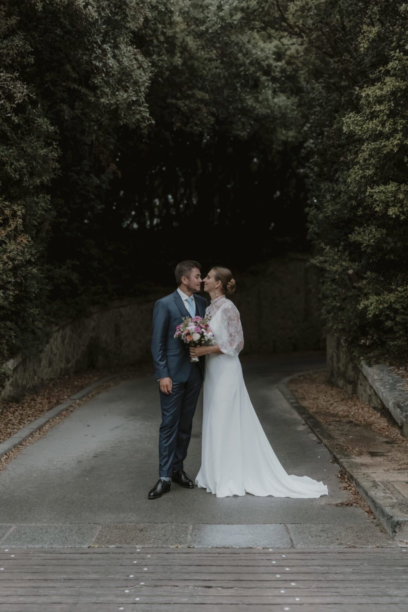 Un marié et une mariée sur un chemin bordé d’arbres à l’Île d’Yeu