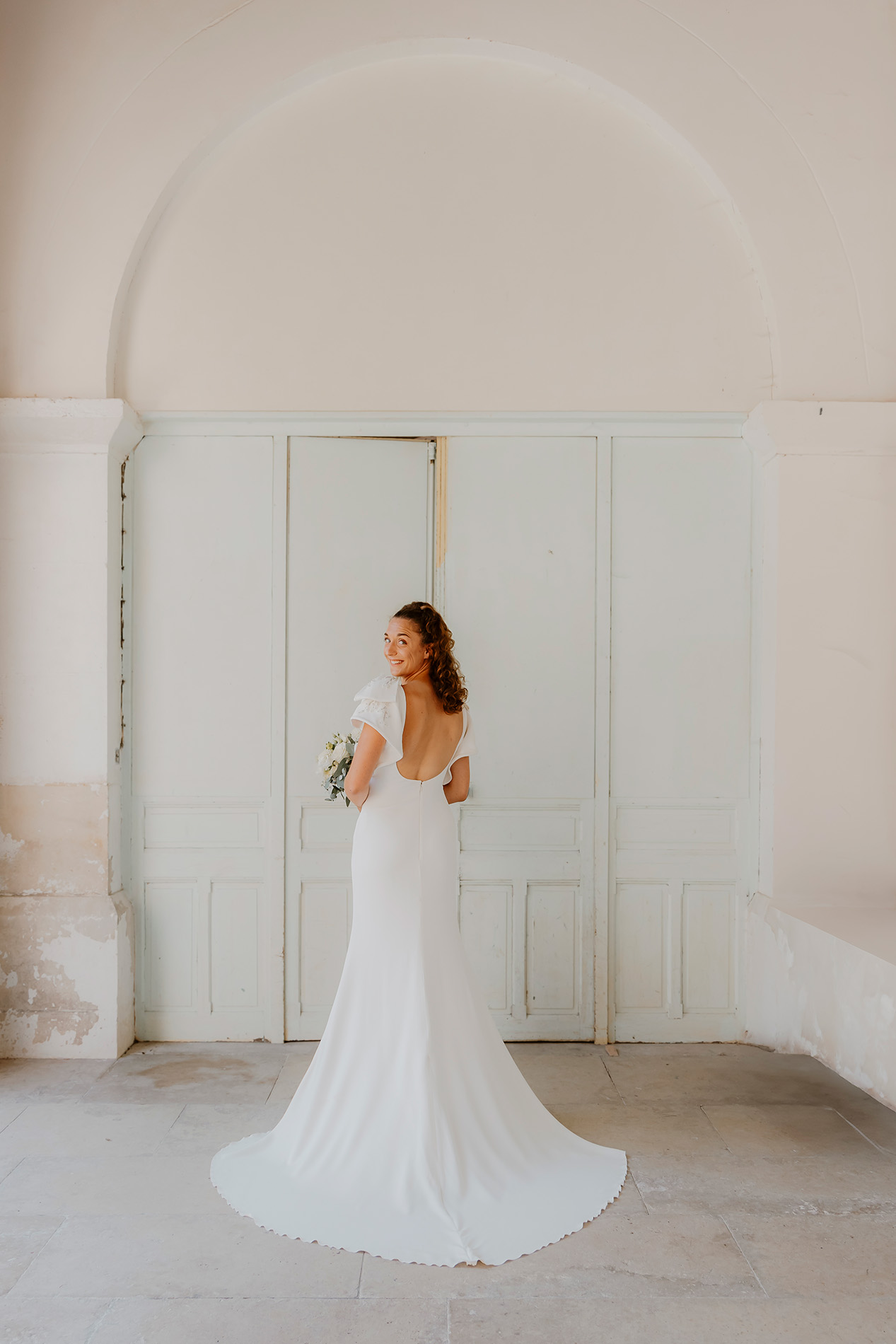 Mariée de dos dans une pièce blanche — photographe de mariage sur la Côte d’Opale