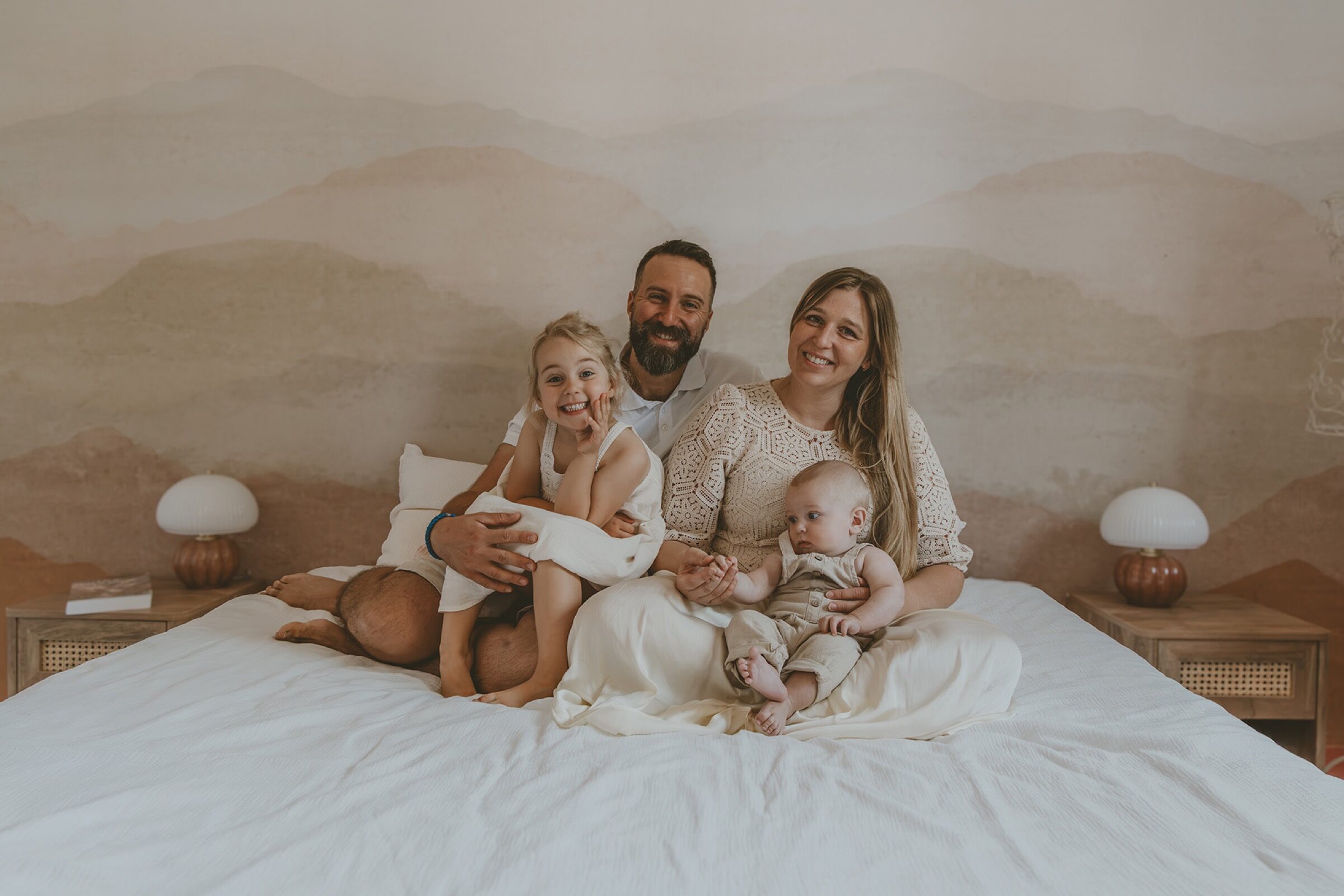 Famille de quatre souriante sur le lit — séance photo de famille, photographe à Wimereux