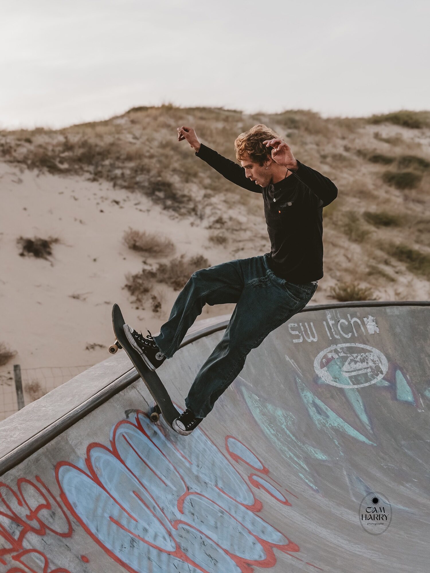 Skateur dans un bowl graffé face aux dunes