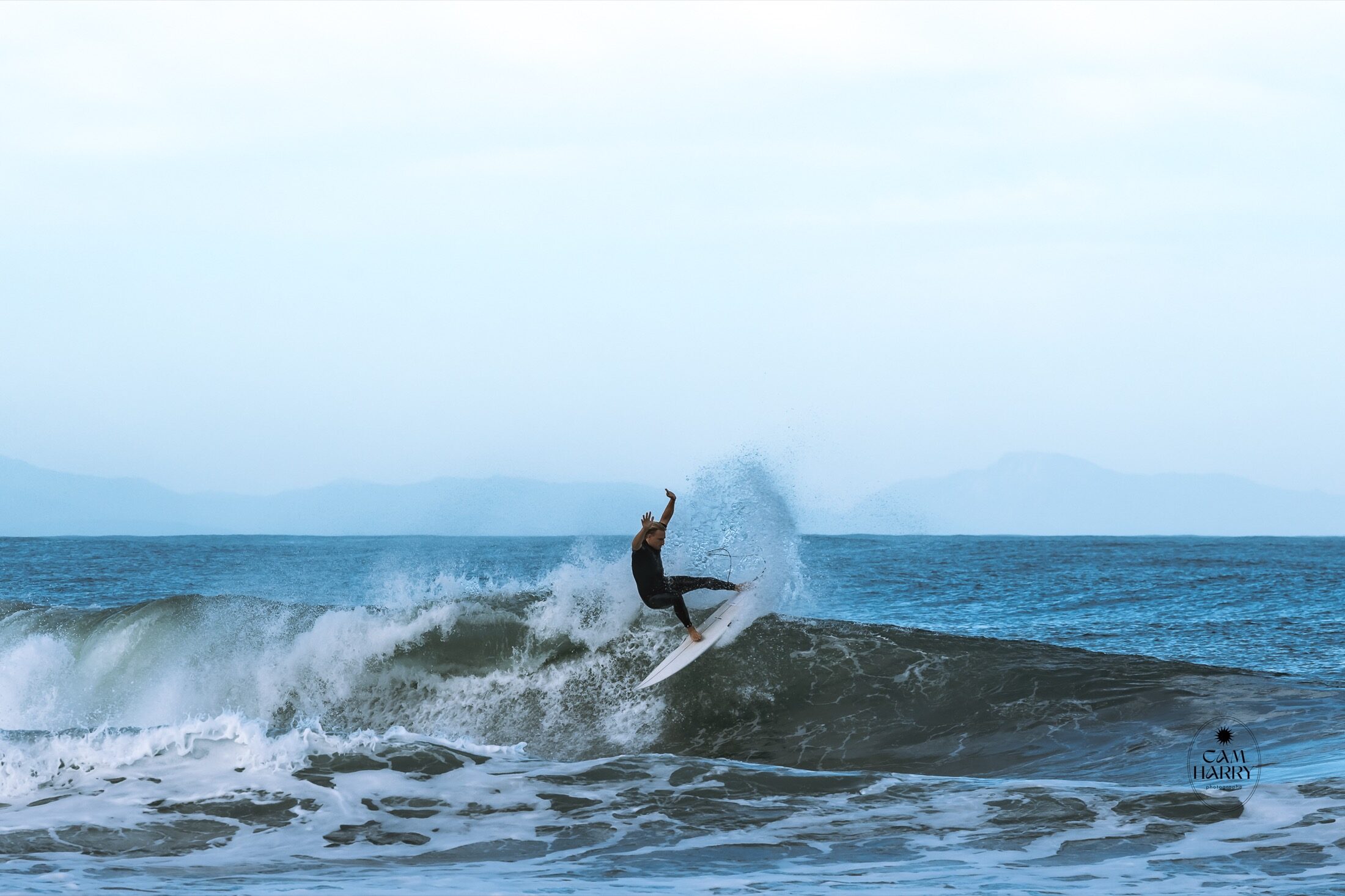 Surfeur en plein virage sur une vague bleue — photographe sport de glisse