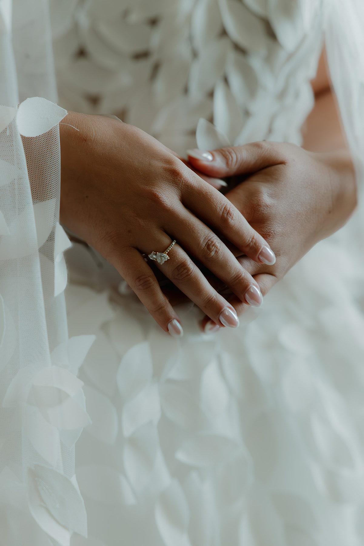 Mains de la mariée et bague de fiançailles posées sur la robe