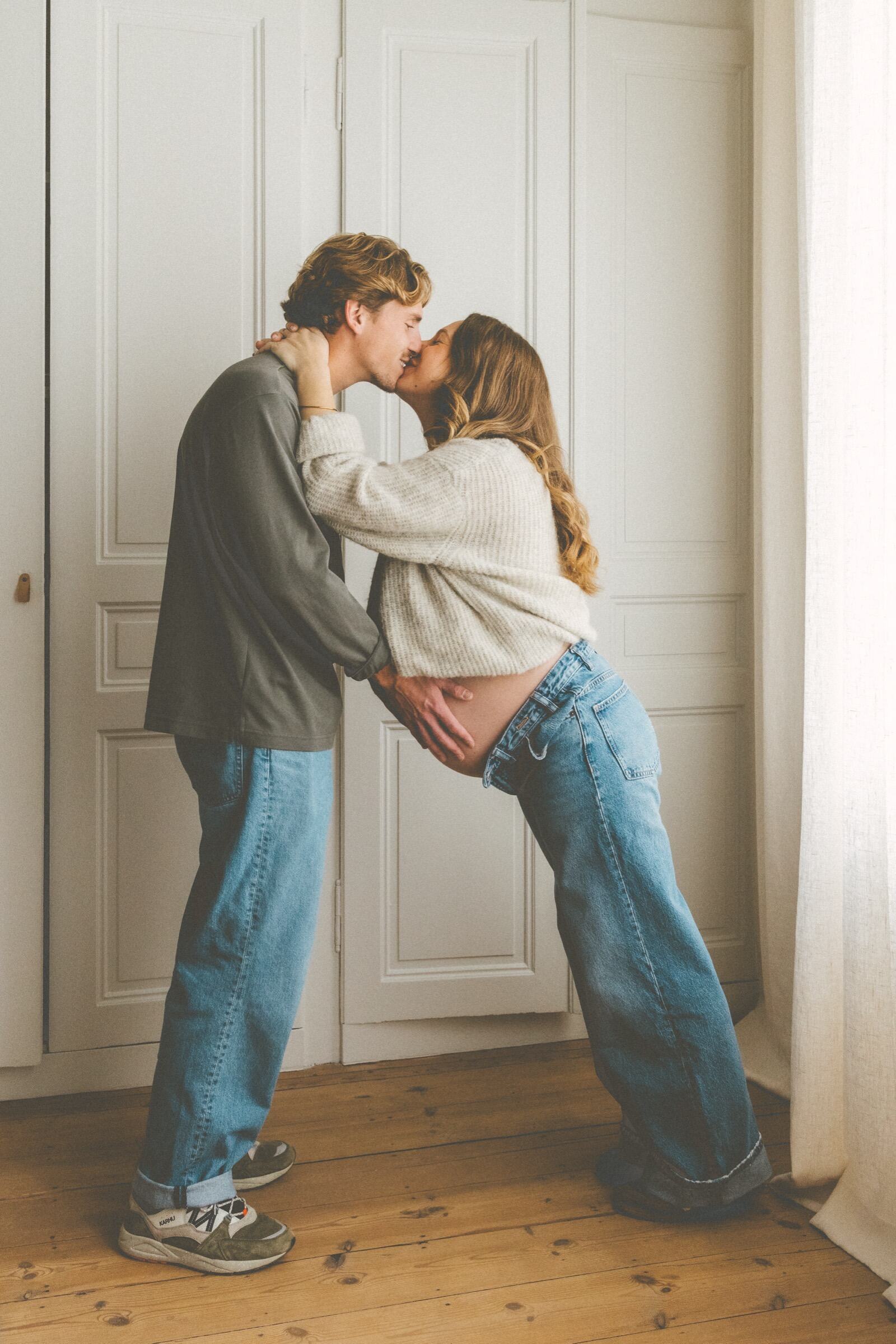 Futurs parents qui s’embrassent devant une double porte — photographe grossesse Wimereux