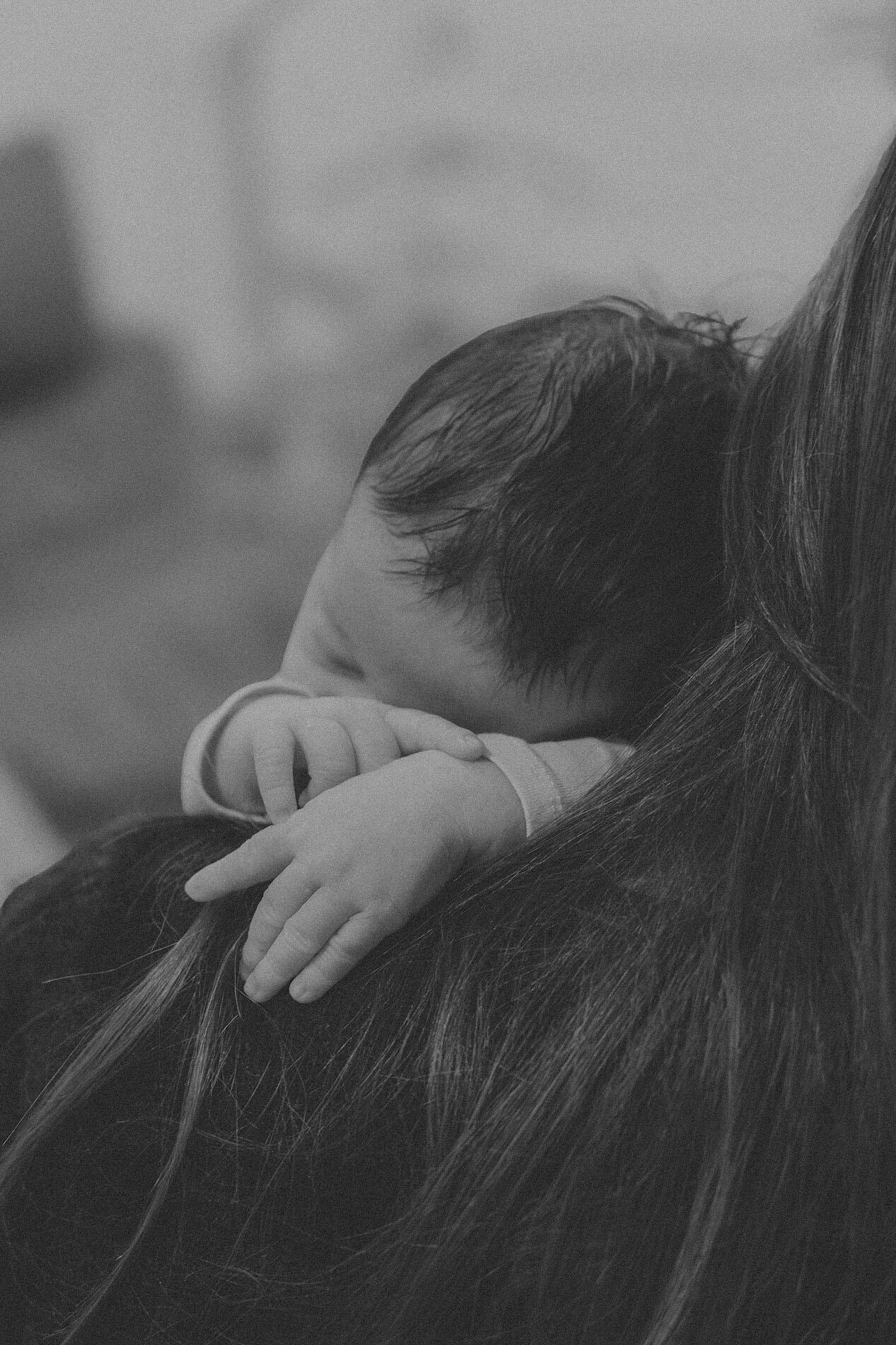 Nouveau-né blotti contre son parent, en noir et blanc — photographe de naissance