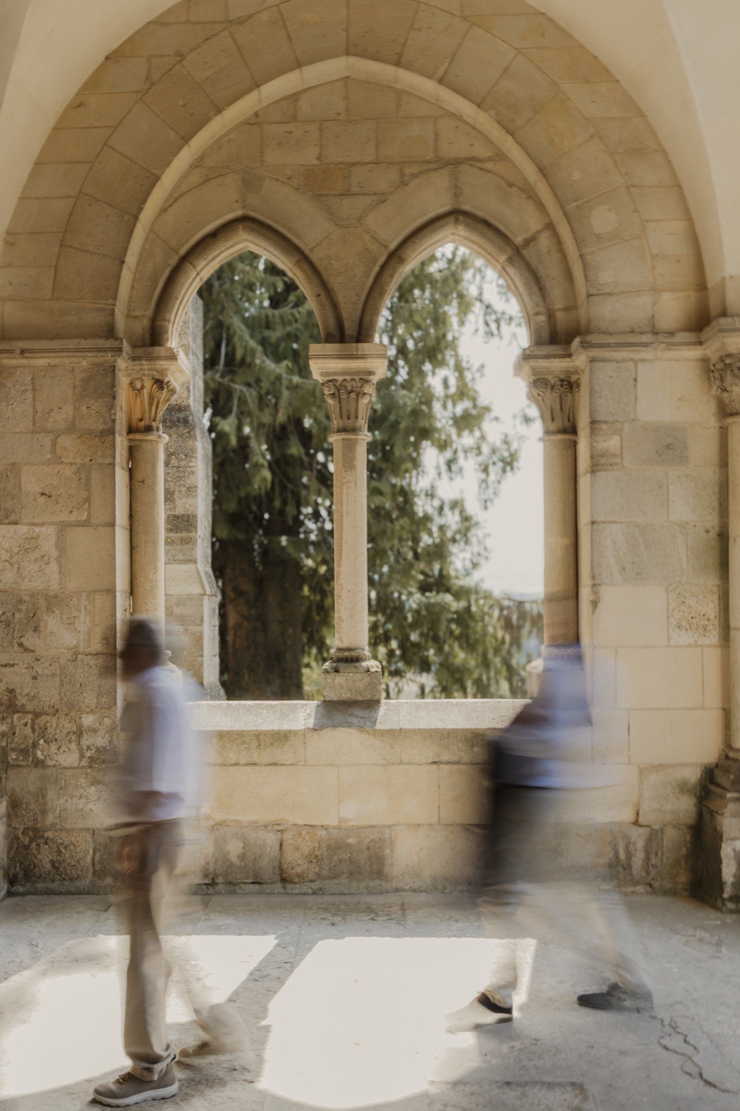 Invités en mouvement sous les arches d’un cloître — reportage photo de mariage