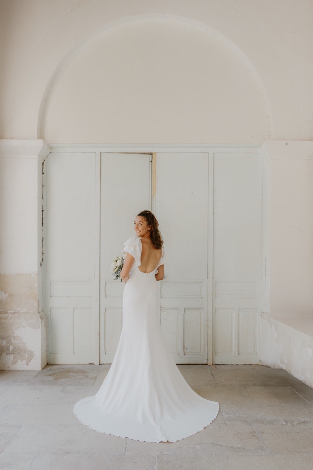 La mariée en robe à traîne dans la lumière d’une pièce blanche — photographe mariage Côte d’Opale